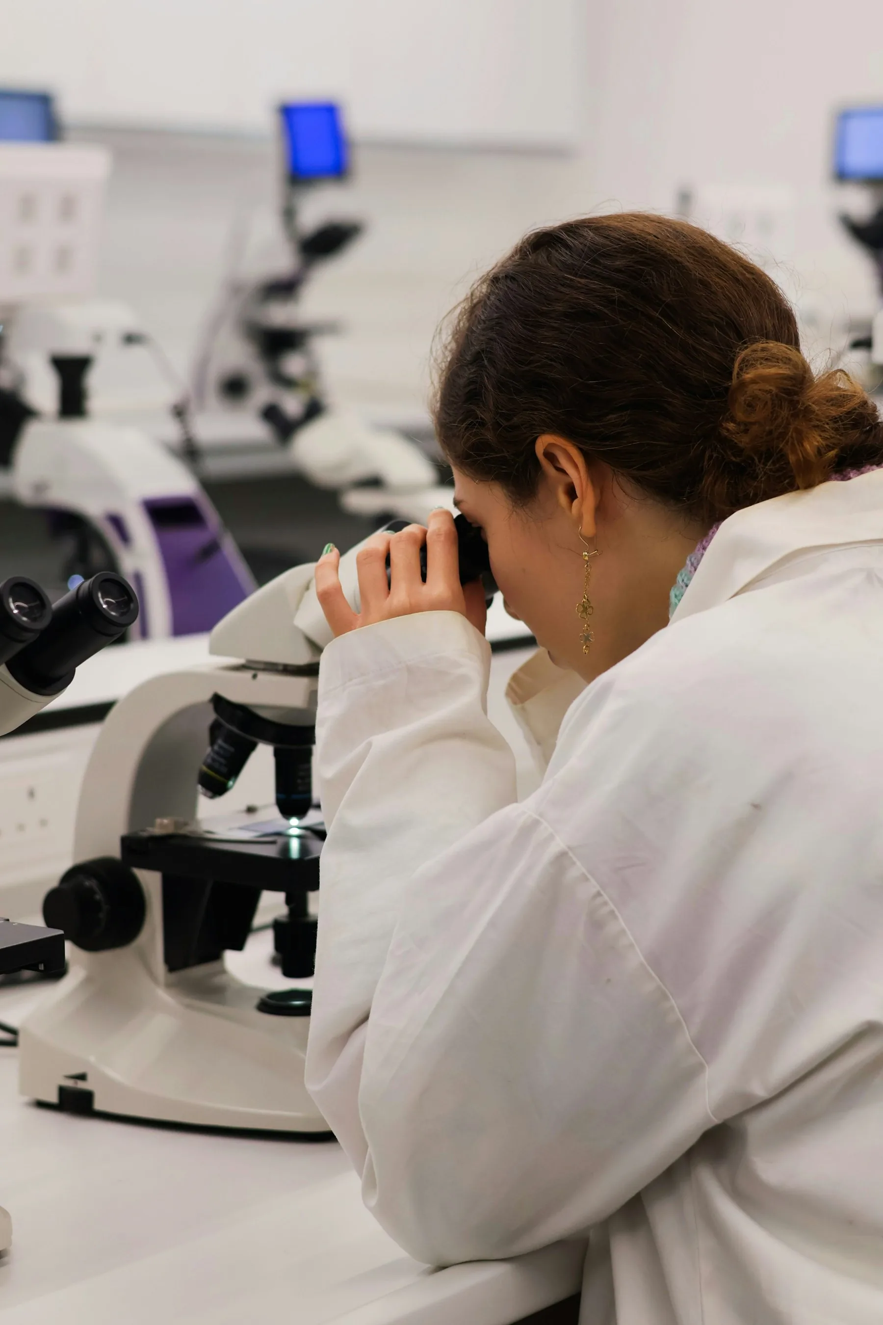 Researcher observing a sample through an optical microscope